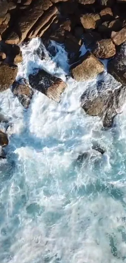 Aerial view of ocean waves crashing against rocks on the shore.