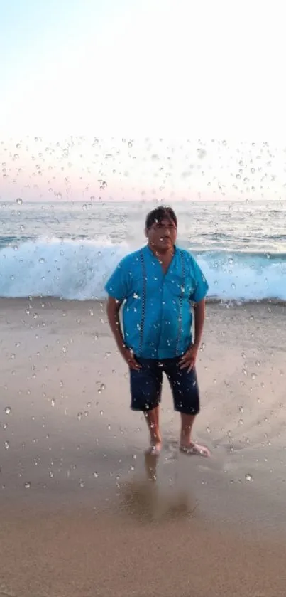 Man standing on sandy beach with ocean waves and water droplets.