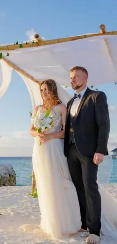 Couple weds under a floral arch at a beach ceremony.