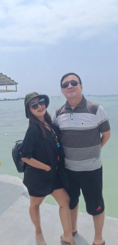 Couple enjoying a sunny day at a picturesque beach with clear blue skies.