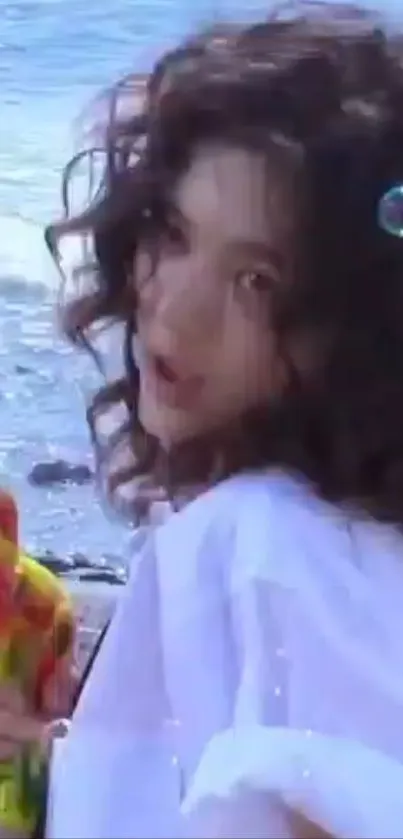 Woman with curly hair at the beach holding a colorful toy.