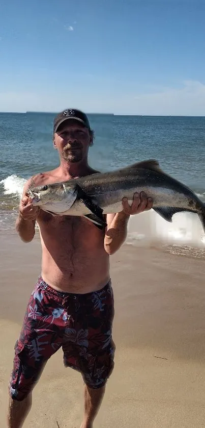 Man holding a fish by the sea on a sunny beach day.