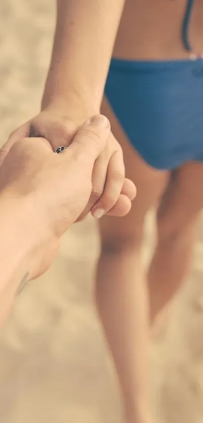 Couple holding hands on sandy beach in summer.