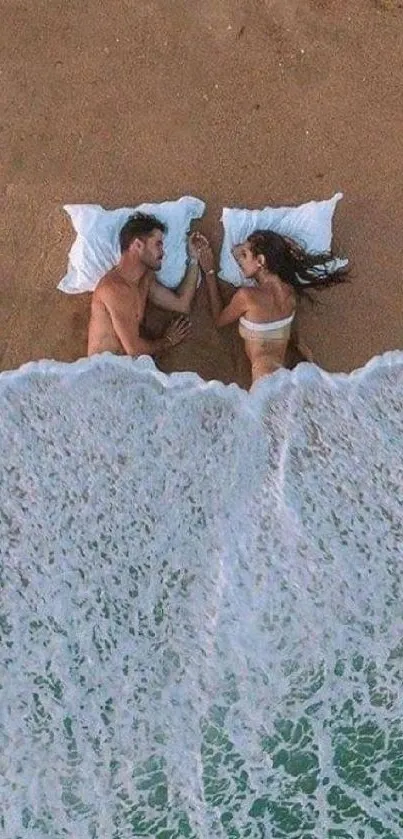 Couple lying on sand as ocean waves gently wash over them.