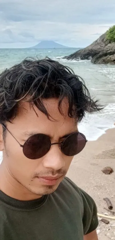 Man in sunglasses at a scenic beach with ocean waves.