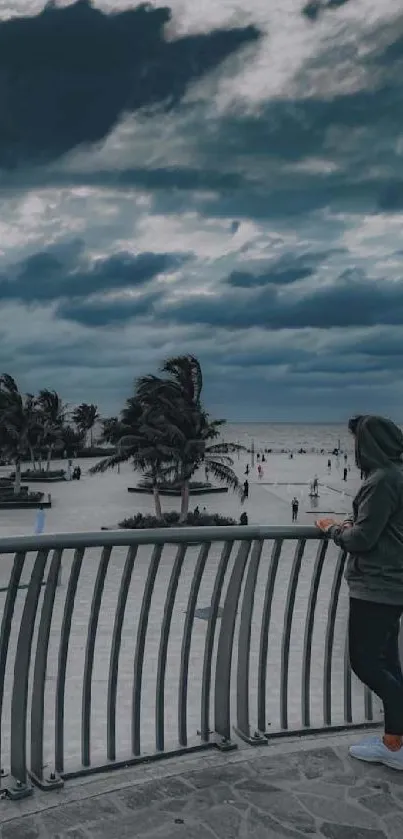 Person overlooking a beach with dramatic clouds in the sky, creating a serene atmosphere.