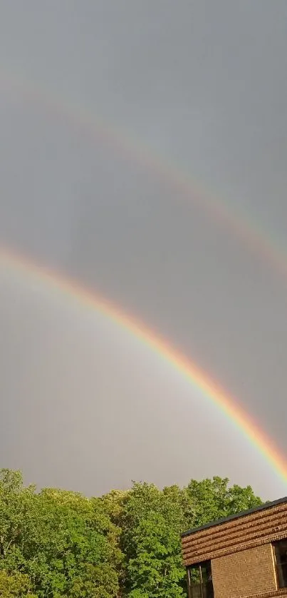 Double rainbow over brick house and green landscape.