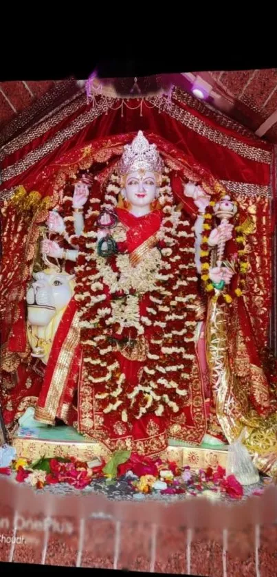 Goddess adorned in red, with flower garlands, on a sacred altar.