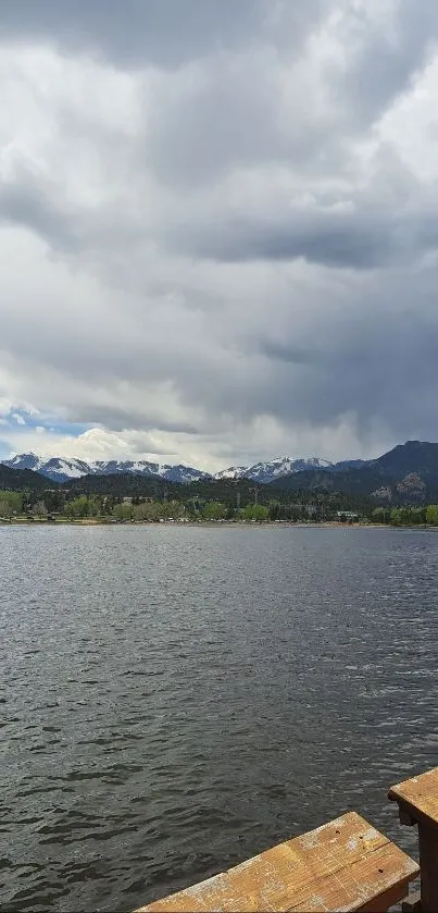 Lakeside view with mountains and cloudy skies, perfect for serene wallpaper.