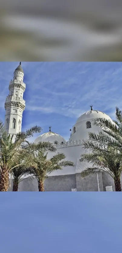 Scenic view of a mosque with palm trees and a clear blue sky.