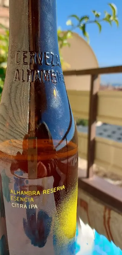 Alhambra Reserva beer bottle on a sunny balcony with city background.