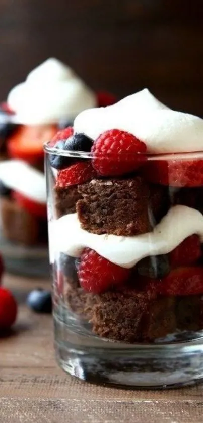 Delicious berry dessert in a glass with chocolate, whipped cream, and fresh fruits.