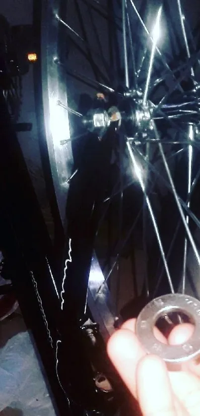 Closeup of a bicycle wheel and hand holding a metal ring.