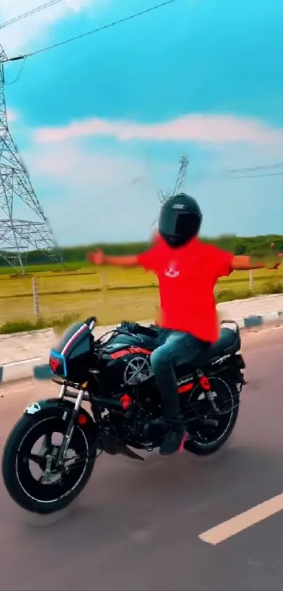 Biker in red shirt riding on open road with clear sky overhead.