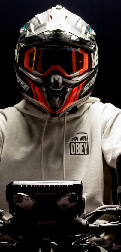 Biker in rugged gear on motorcycle with a dark backdrop.