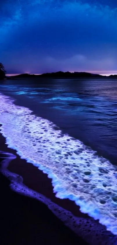 Bioluminescent waves gently illuminate a dark ocean shore under a night sky.