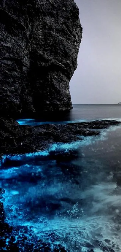 Bioluminescent waves along a rocky coastline at night.