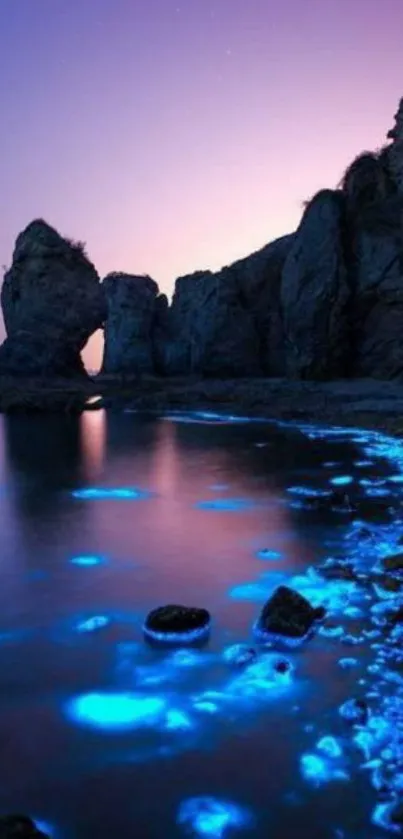 Bioluminescent waves hitting rocky cliffs at dusk with a violet blue sky.