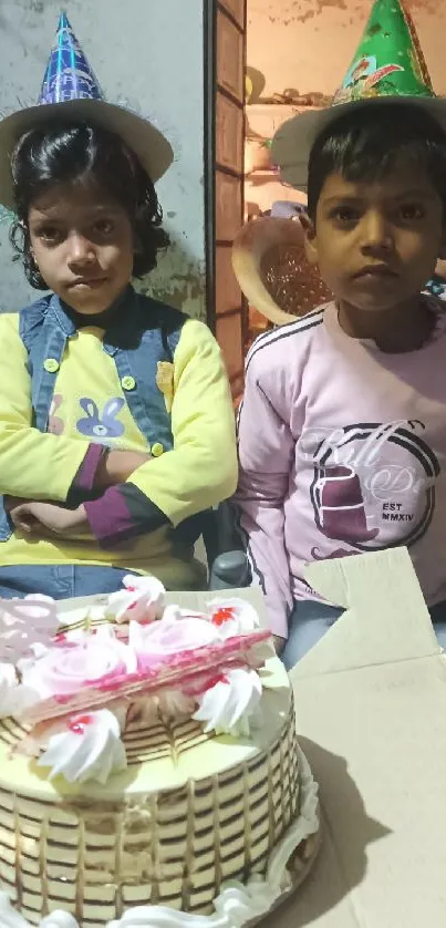 Two children celebrating with cake and party hats.