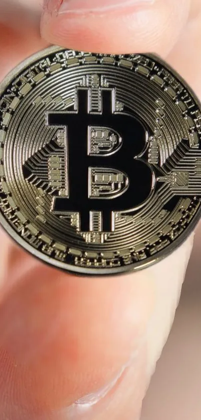 A hand holding a shiny Bitcoin coin wallpaper.