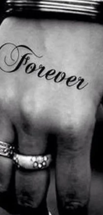 Black and white hand with 'Forever' tattoo and rings.