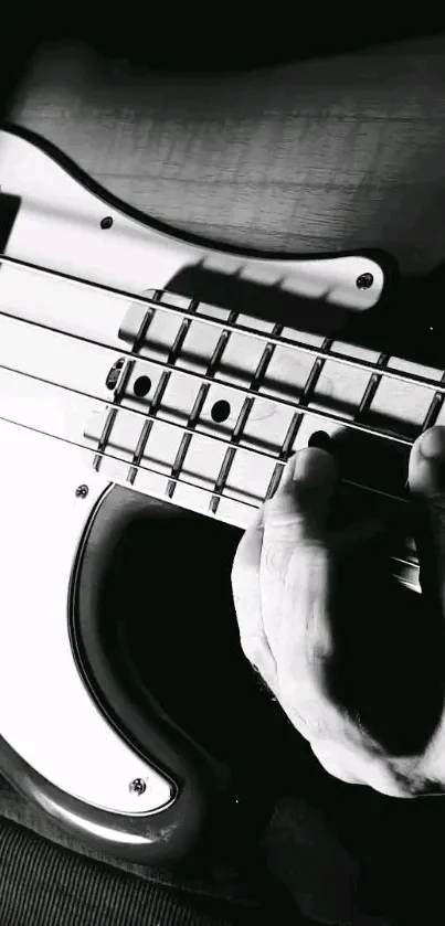 Black and white close-up of a hand playing guitar strings.