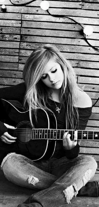 Black and white photo of a guitarist sitting with guitar.