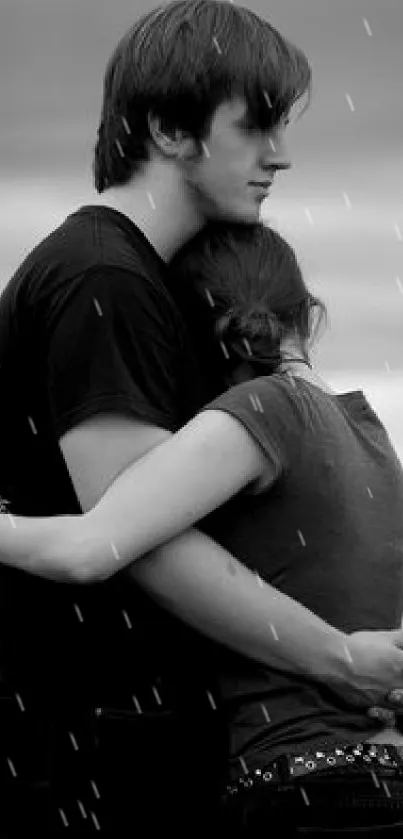 Black and white photo of couple embracing by the sea.