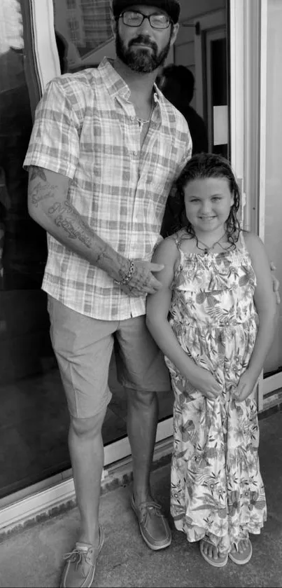 Black and white wallpaper of a father and daughter standing together, exuding warmth.