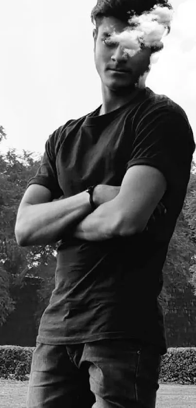 Black and white portrait of a young man in a park posing with arms crossed.