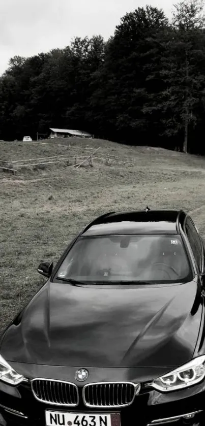 A sleek black car on a scenic forest road, perfect for mobile wallpaper.