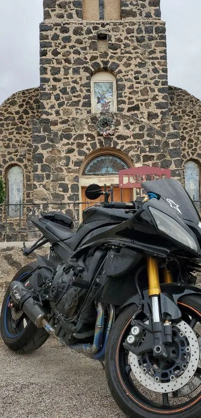 Black motorcycle in front of a stone church.