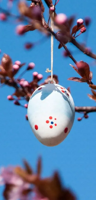 Easter eggs hanging from blossoming branches with a blue sky background.