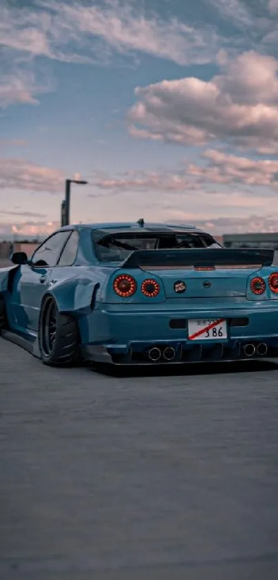 Blue sports car under a stunning sunset sky with urban background.