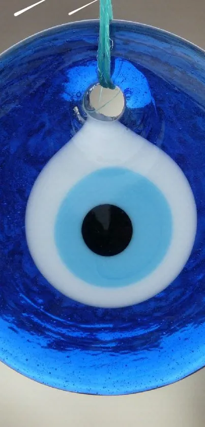 Blue evil eye amulet hanging against blurred background.