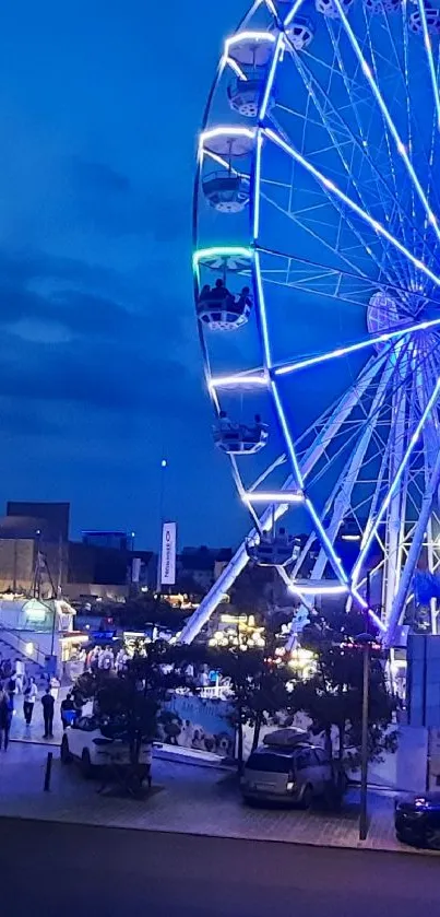 Blue Ferris wheel glowing at night in cityscape.