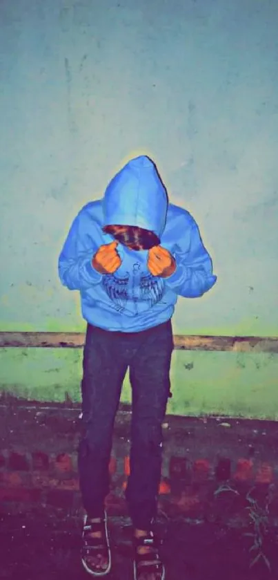 Person in blue hoodie standing against wall.