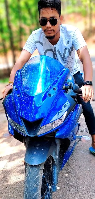 Man riding a blue motorcycle on a road.