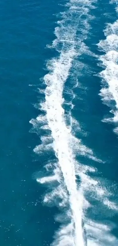 Aerial view of white trails over deep blue ocean waves.