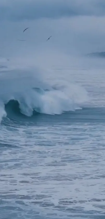 Blue ocean waves crashing under a cloud-filled sky.