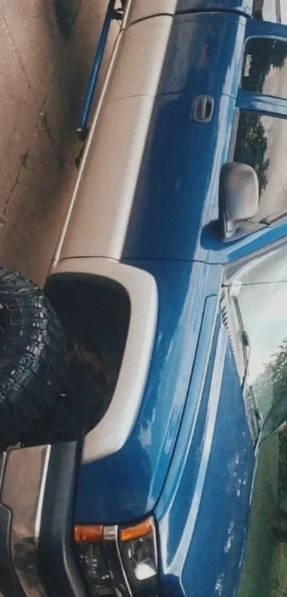 Blue pickup truck parked outdoors with rugged tires.