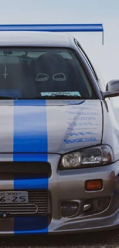 Sleek blue racing car with bold stripes on a clear day.