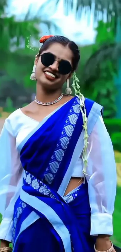 Woman in a blue saree standing in a green garden.