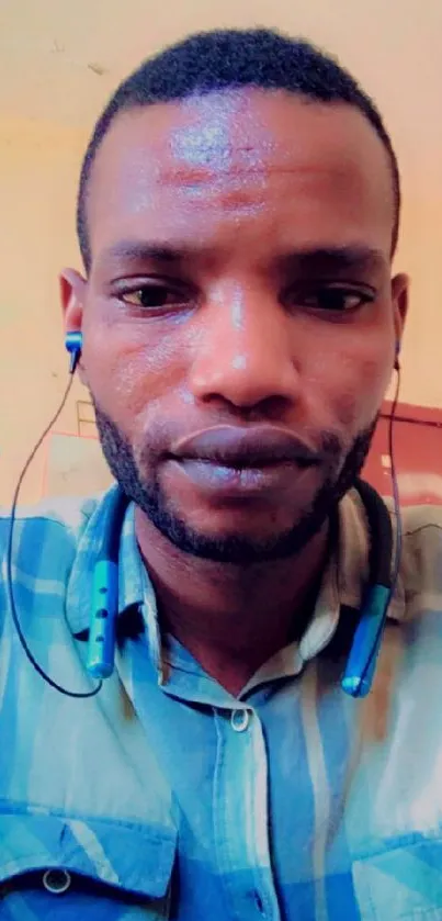 Portrait of a young man in a blue shirt with earphones.