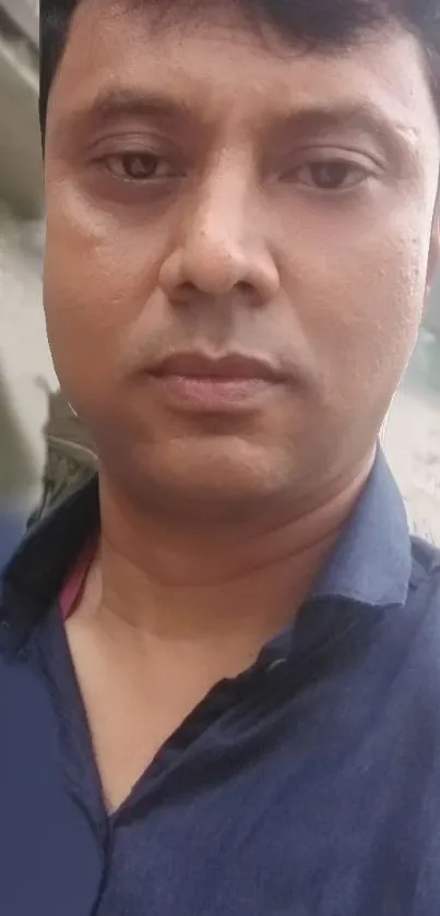 Man in navy blue shirt with blurred background wallpaper.