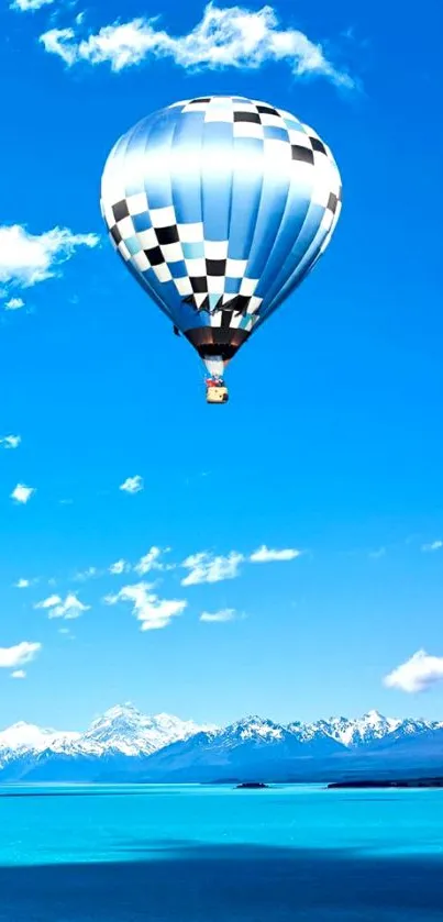 Hot air balloon soaring in a vibrant blue sky over mountains.