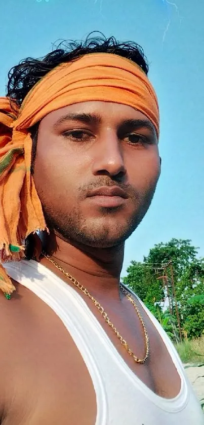 Man wearing an orange headscarf under a blue sky with lightning.