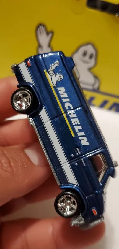 Detailed blue toy van with logo on yellow background.