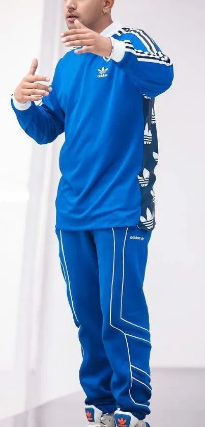 Person in a stylish blue tracksuit with fashion elements on a clean background.