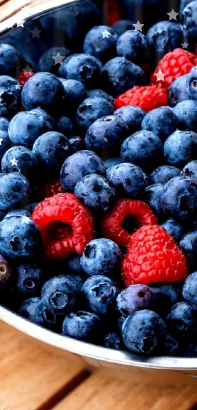 A bowl of fresh blueberries and raspberries on a wooden surface.